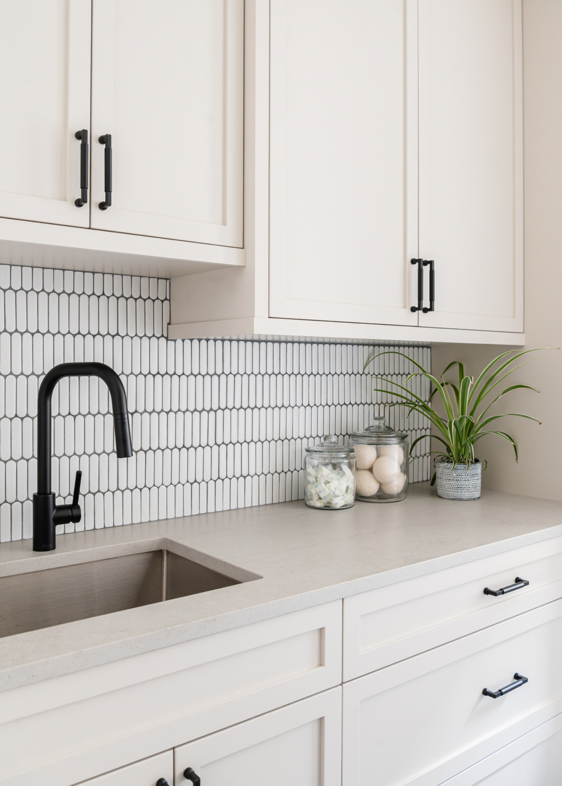 Custom laundry room cabinetry with a picket tile backsplash, quartzite counter and undermount sink in an Elmhurst, IL home by Dara Agruss Design