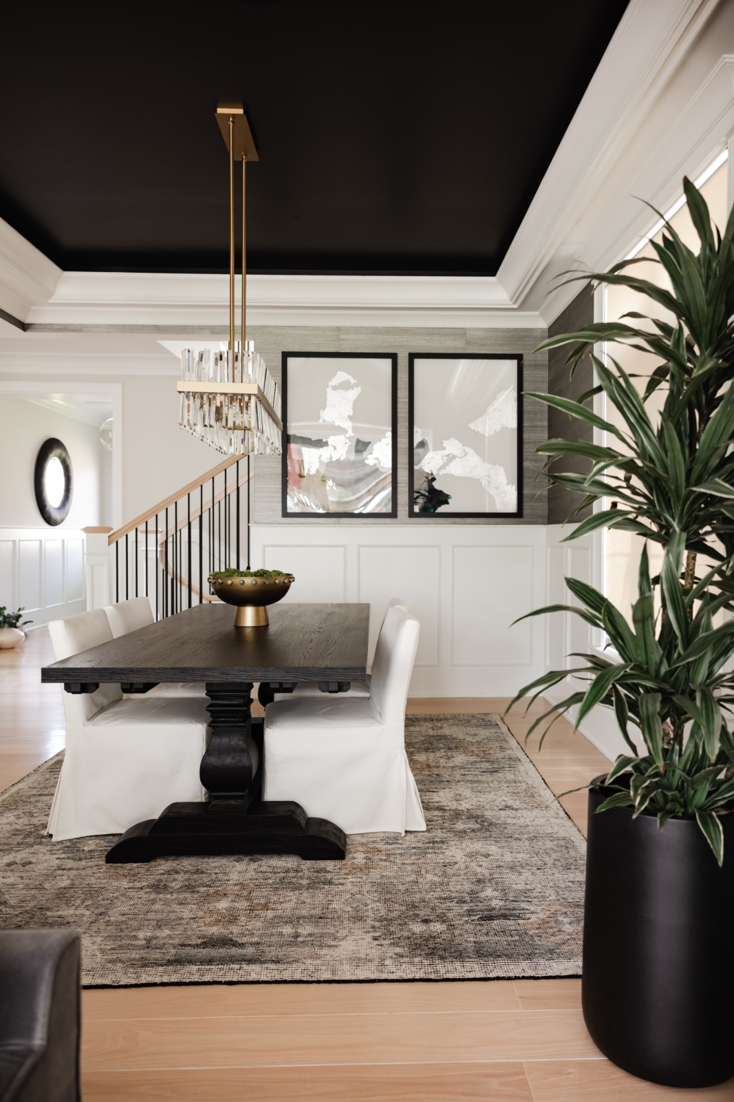 Dining room with a dark pedestal table, brass chandelier and gallery wall in an Elmhurst, IL home by Dara Agruss Design