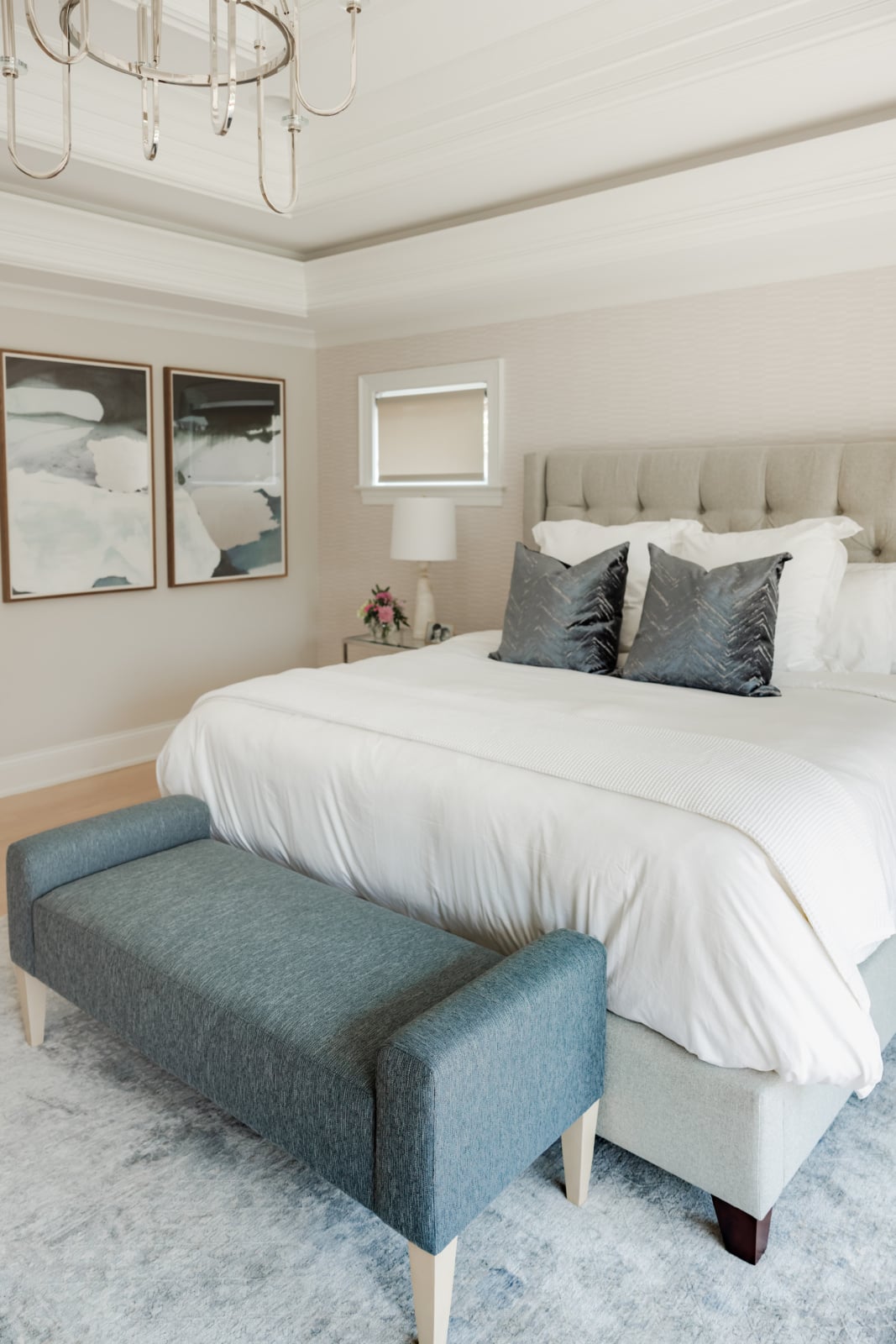 Primary bedroom with an upholstered bed, teal bench and framed art in an Elmhurst, IL home by Dara Agruss Design