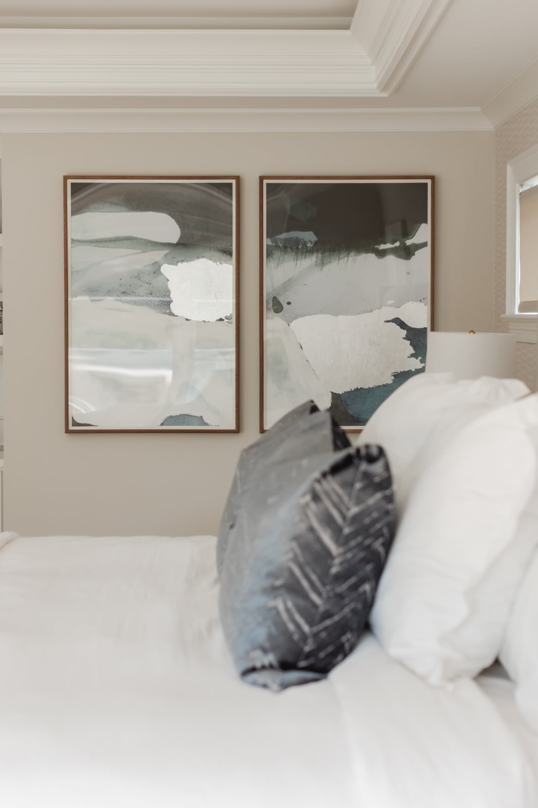 Bedside detail with layered bedding and a diptych above the headboard in an Elmhurst, IL home by Dara Agruss Design