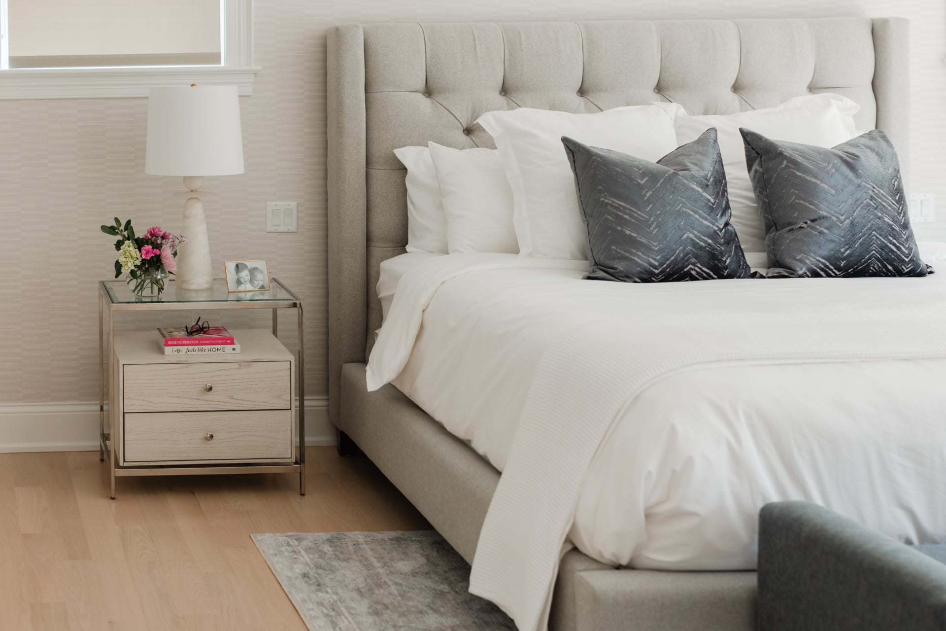 Primary bedroom with a tufted headboard, layered neutral bedding and a mirrored nightstand in an Elmhurst, IL home