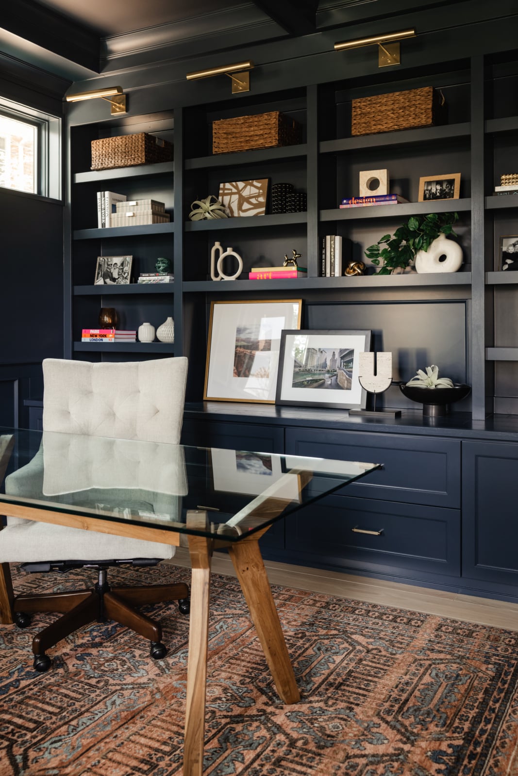Built-in navy shelving styled with books and art above a desk in an Elmhurst, IL study by Dara Agruss Design