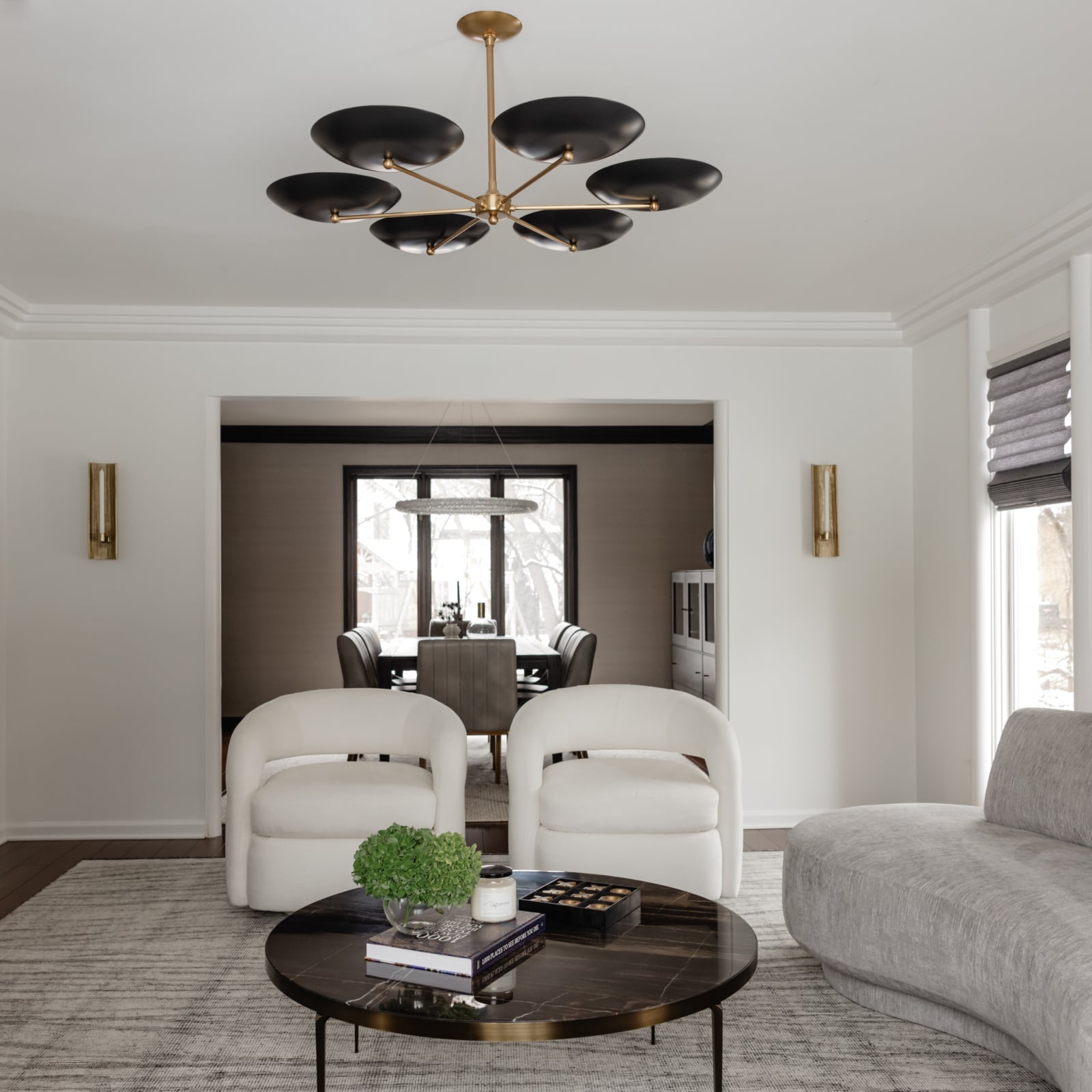 Living room with curved lounge chairs and a black disc chandelier in an Oak Brook, IL home by Dara Agruss Design