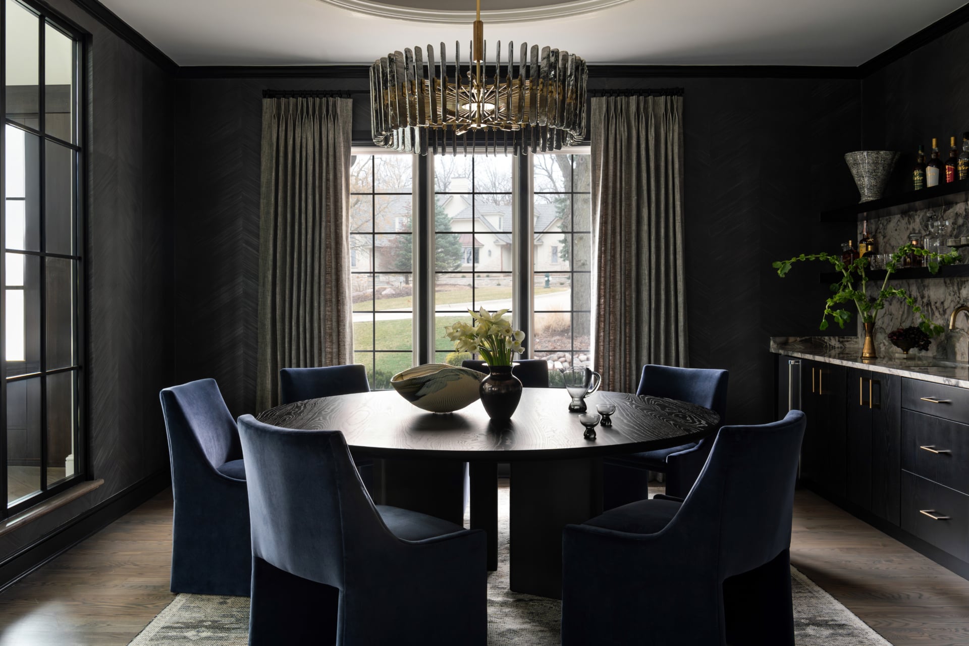 Dark dining room with pinch-pleated drapery panels mounted near the ceiling and falling to the floor, framing a black-trimmed window, from The Modern Collector project in Oak Brook by Dara Agruss Design
