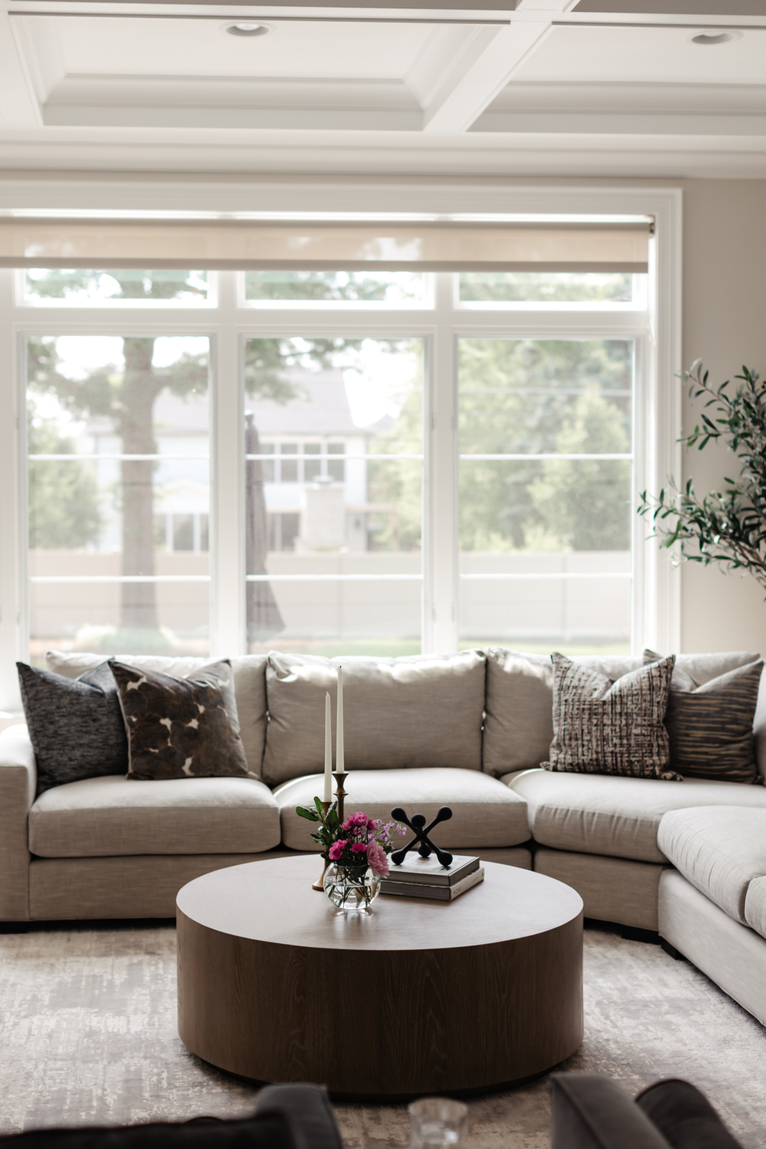 Corner sectional with layered patterned cushions beneath a bank of windows