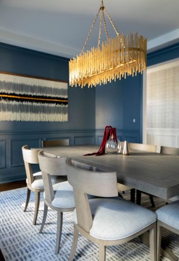 Dining room with dark blue walls, beige dining set, and statement chandelier