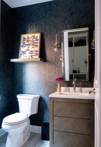Washroom with dark blue walls, wooden cabinets, and white sink