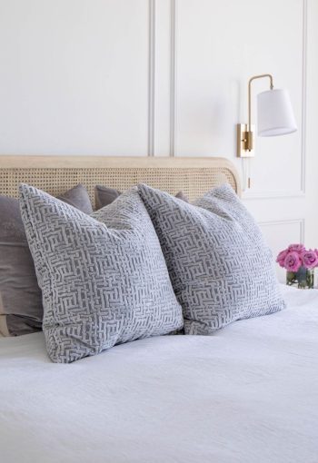 Bed with wooden headboard and gray sheets and pillows